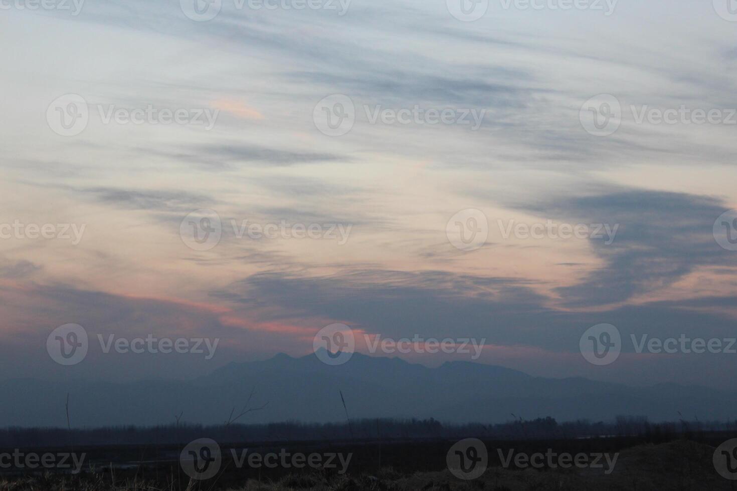 A plane flying over a field with mountains in the background photo