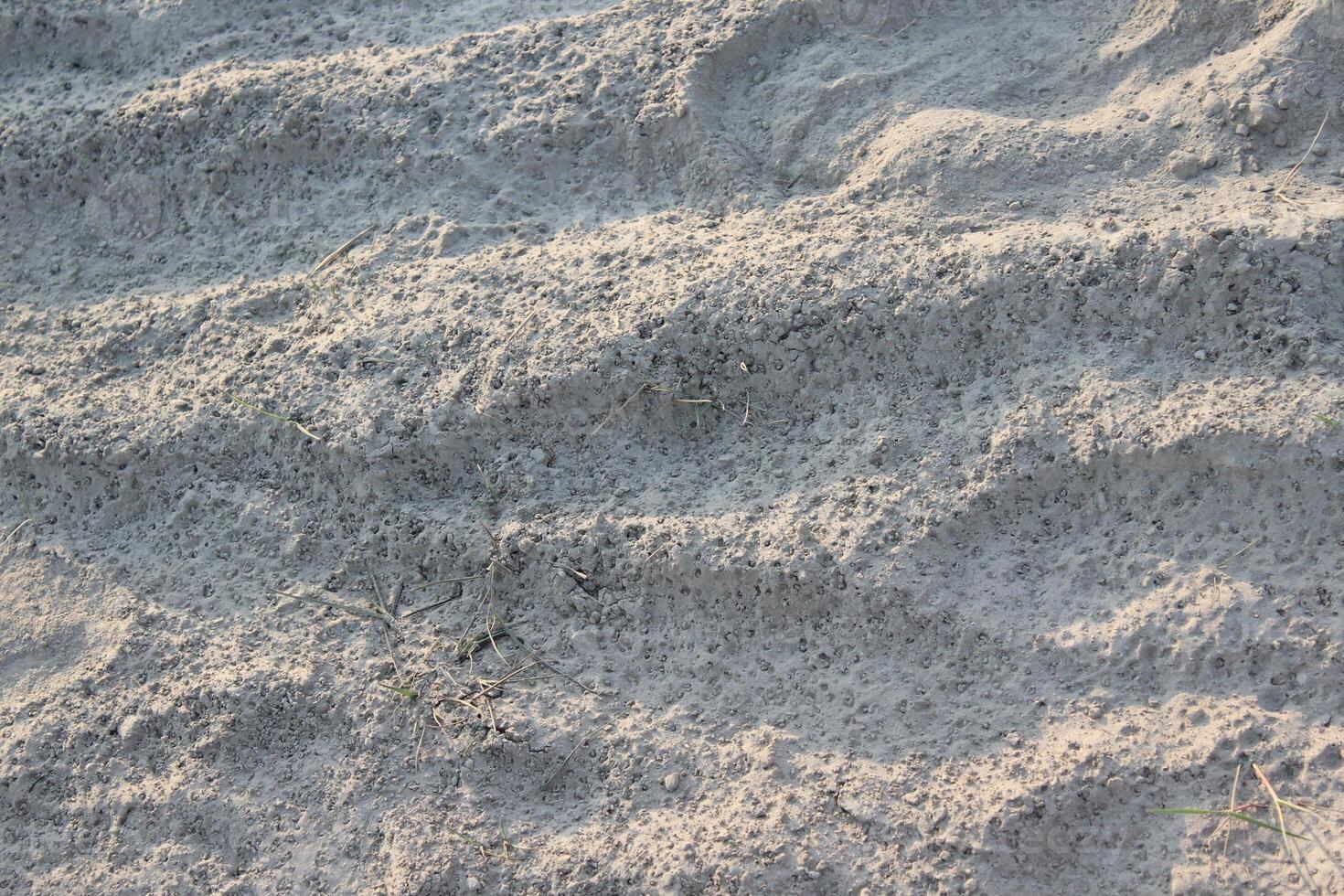 Dry, sandy terrain with visible footprints and textured surface photo