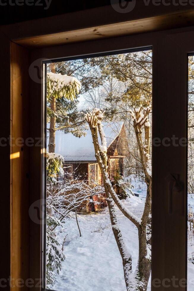 view through window of snowy yard with wooden hu photo