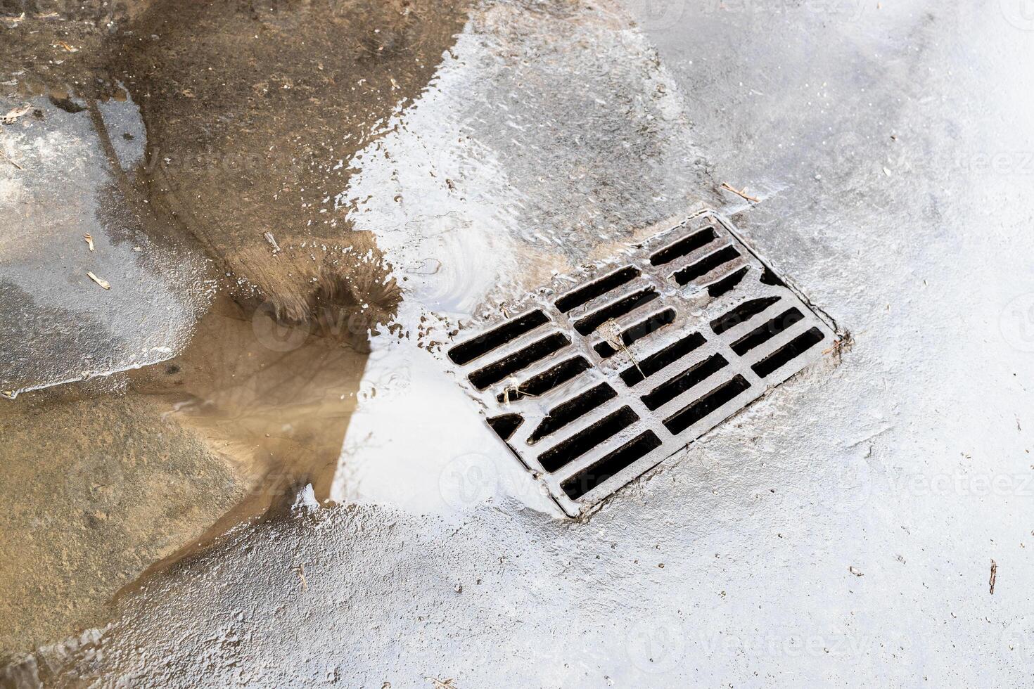 wet cast iron grate of street sewer and puddle photo