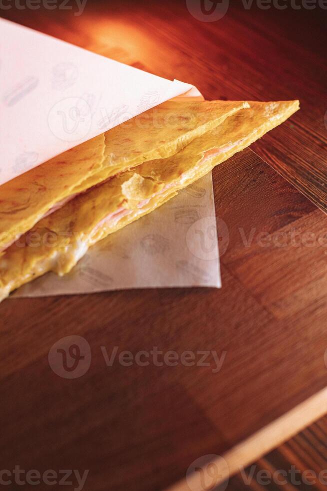 thin pancakes with ham and cheese in an envelope are placed on a serving surface in a restaurant photo