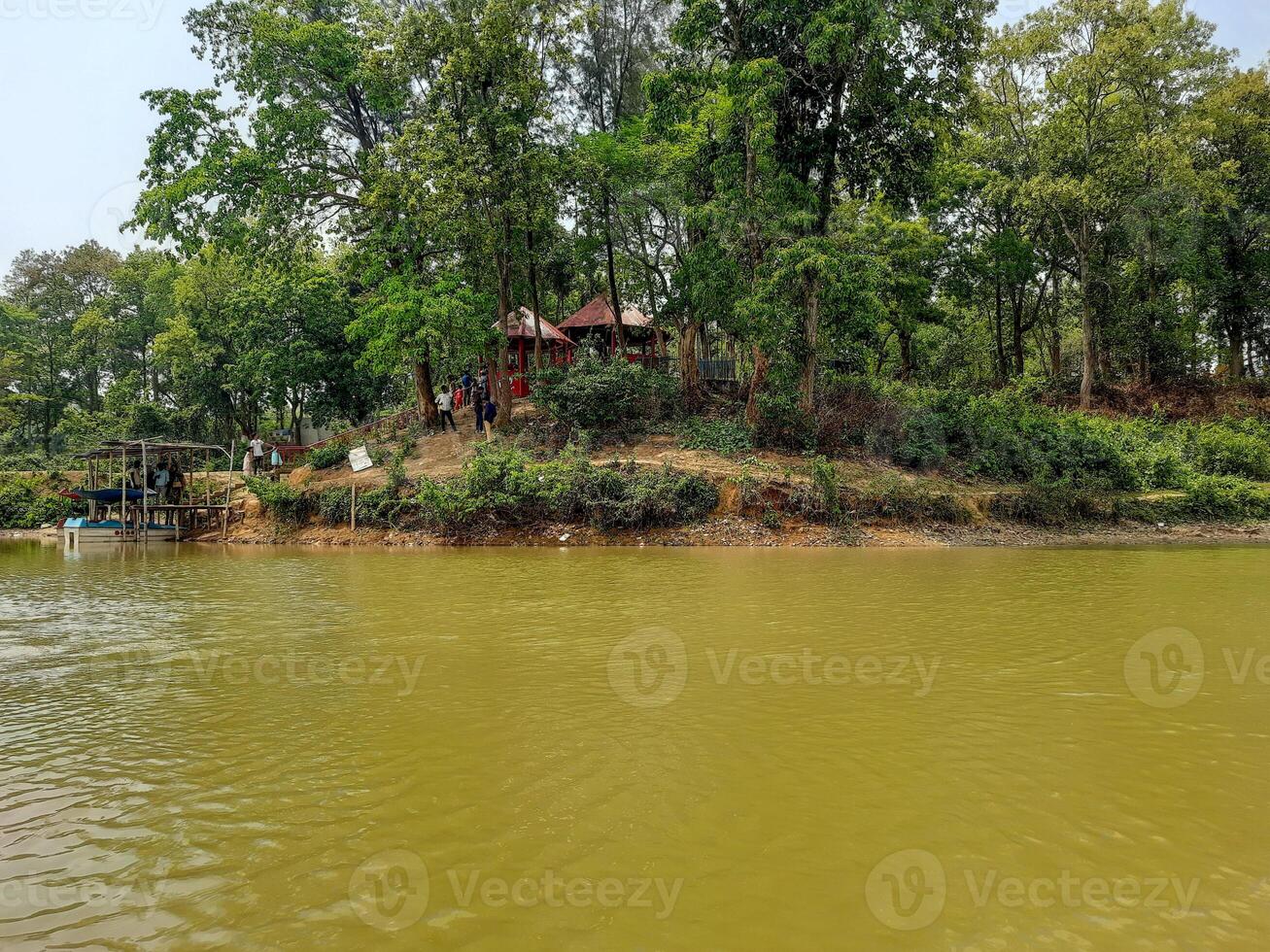a house on the bank of a river with trees in the background photo