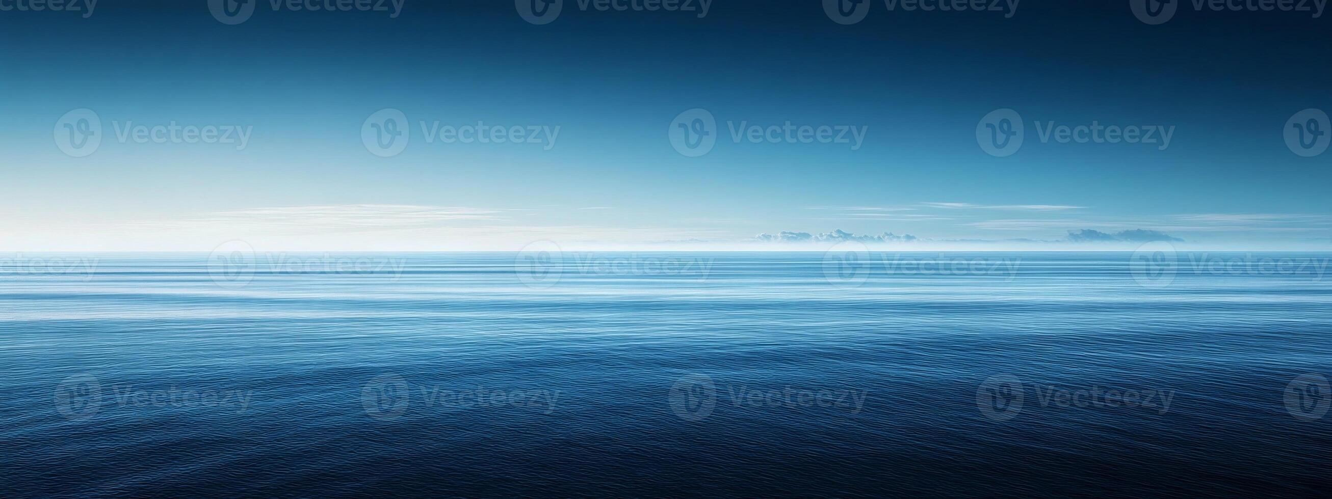 Expansive horizon meeting the tranquil depths of a serene blue ocean under a clear sky at dawn photo
