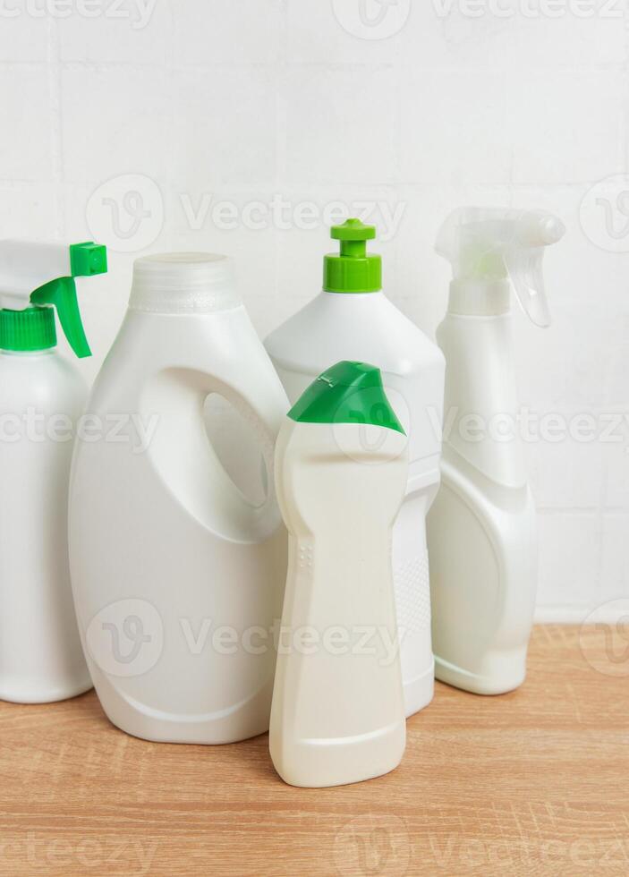 Cleaning products standing on wooden tabletop in front of white tiles wall photo