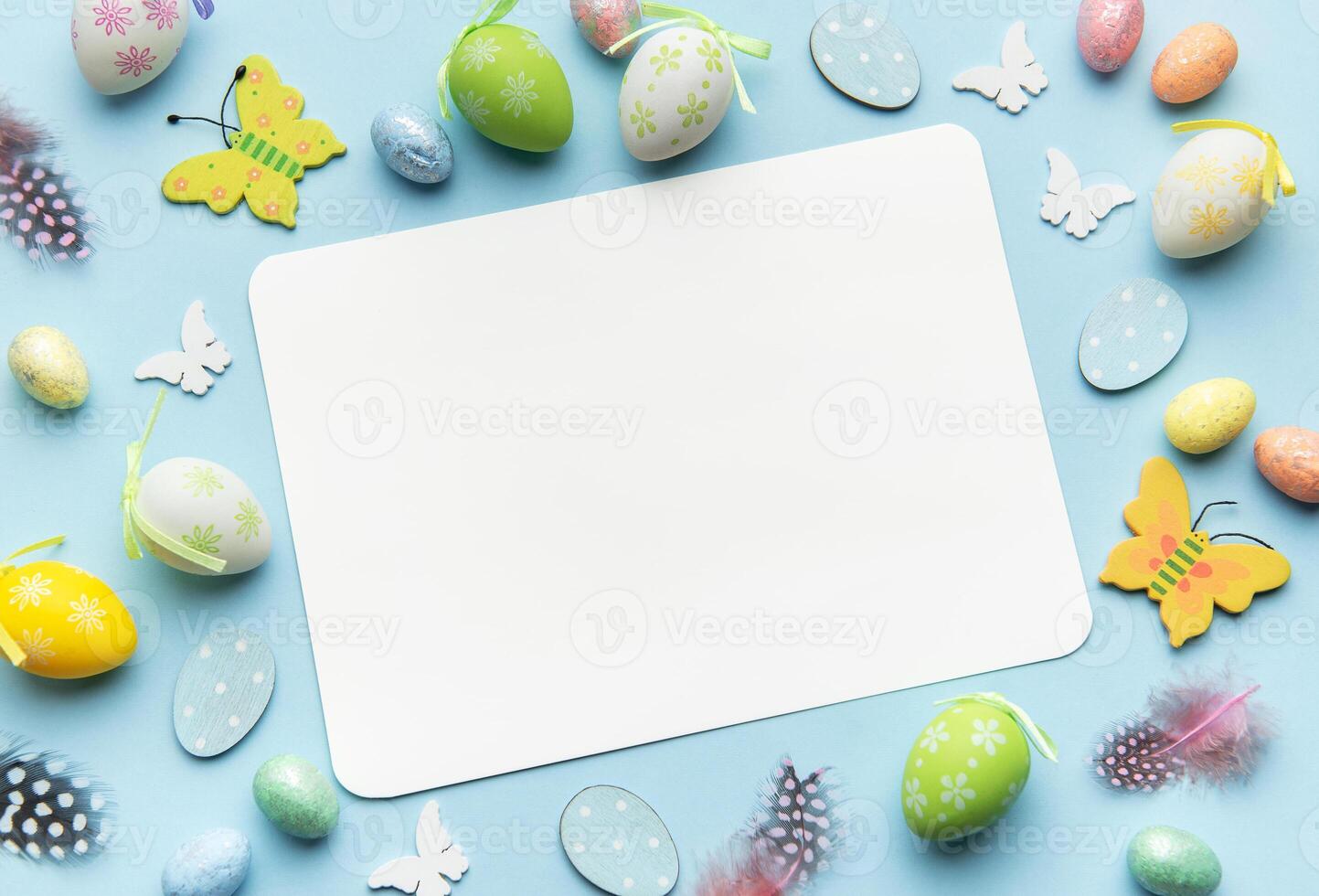 Easter decoration forming frame around blank card on blue background top view photo