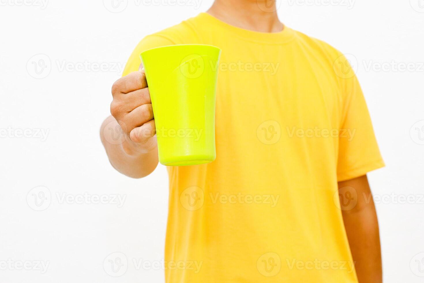 Bright yellow t-shirt, person holding a radiant green drinking cup against a white background photo