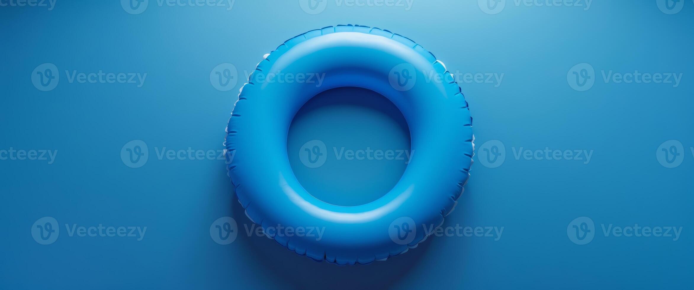 Bright blue inflatable pool ring resting on a solid blue background in a serene and calm setting photo