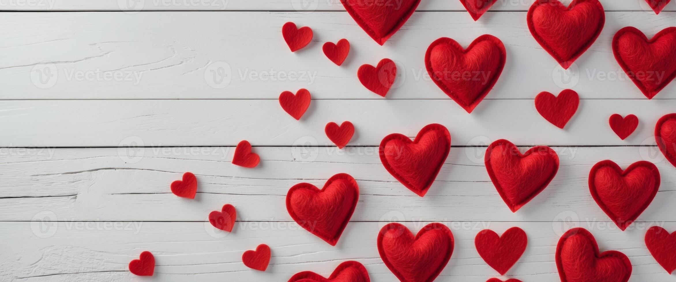 Red felt hearts arranged on a white wooden background creating a Valentine's Day themed border with copy space photo