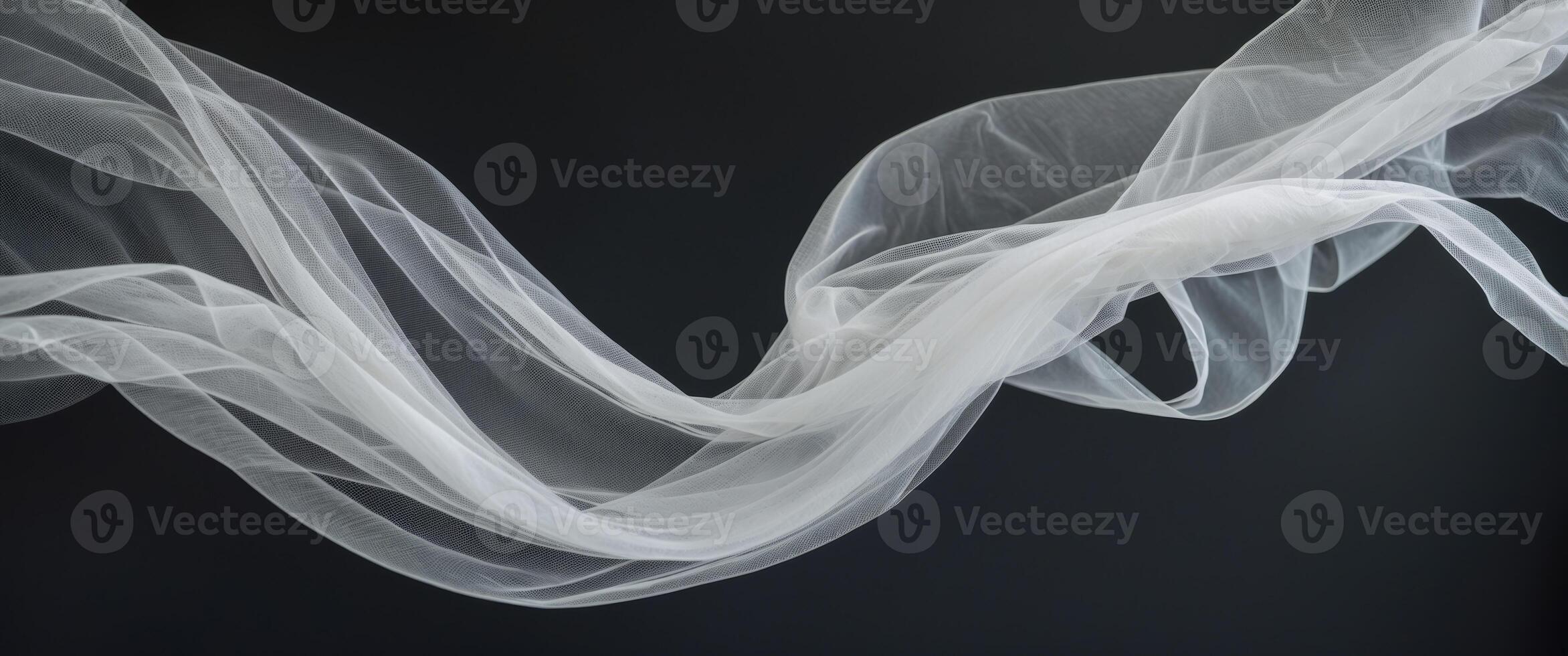 Elegant curves and shapes created by flowing delicate white tulle fabric on a black background. photo