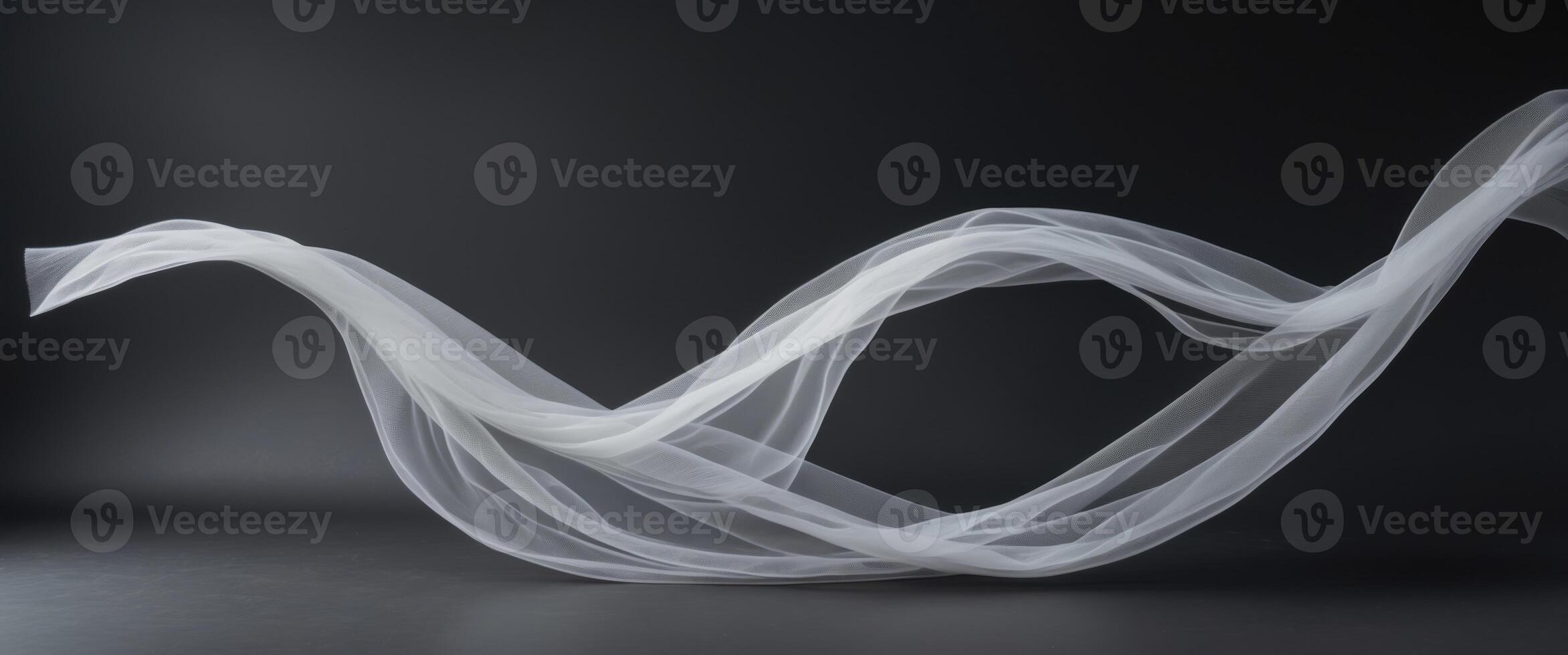 Elegant curves and shapes created by flowing delicate white tulle fabric on a black background photo