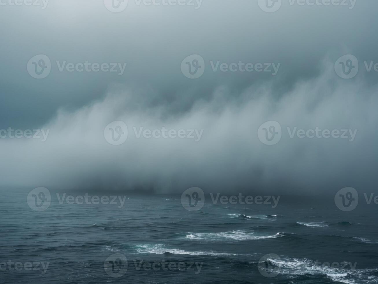 Fog rolling over a deep blue ocean water surface creating a mystical and moody atmosphere photo