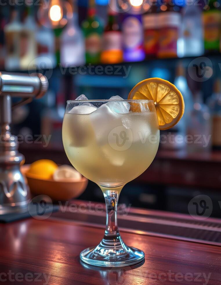 Refreshing cocktail served with ice and lemon slice at a vibrant bar during the evening hours photo
