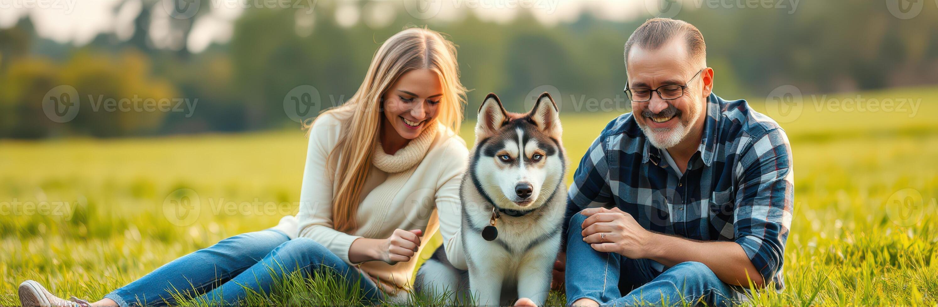 Couple enjoys quality time with their dog in a sunny meadow during late afternoon photo