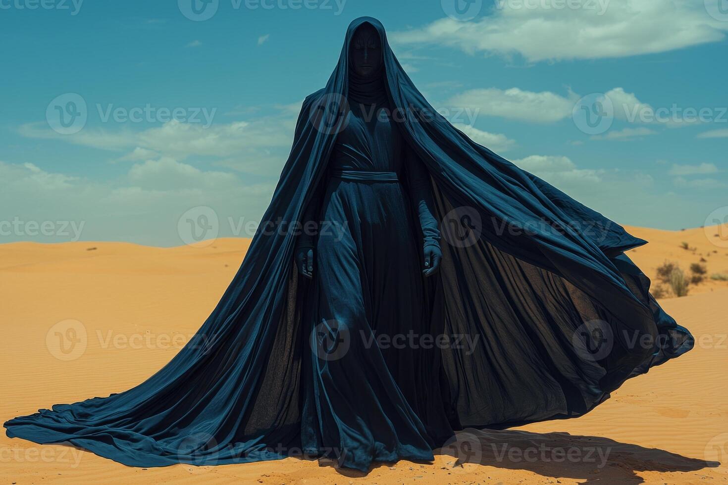 man dressed in dark blue jubba and taqiyah cap stands in open desert landscape. wind lifts fabric of his robe as he embraces spirit of Eid al Fitr pride and tradition photo