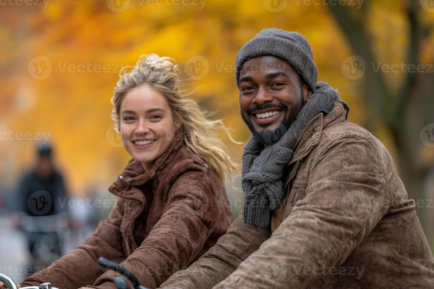 Two happy individuals ride bicycles in city park during autumn. Their joyful expressions and bright surroundings create lively and warm atmosphere photo