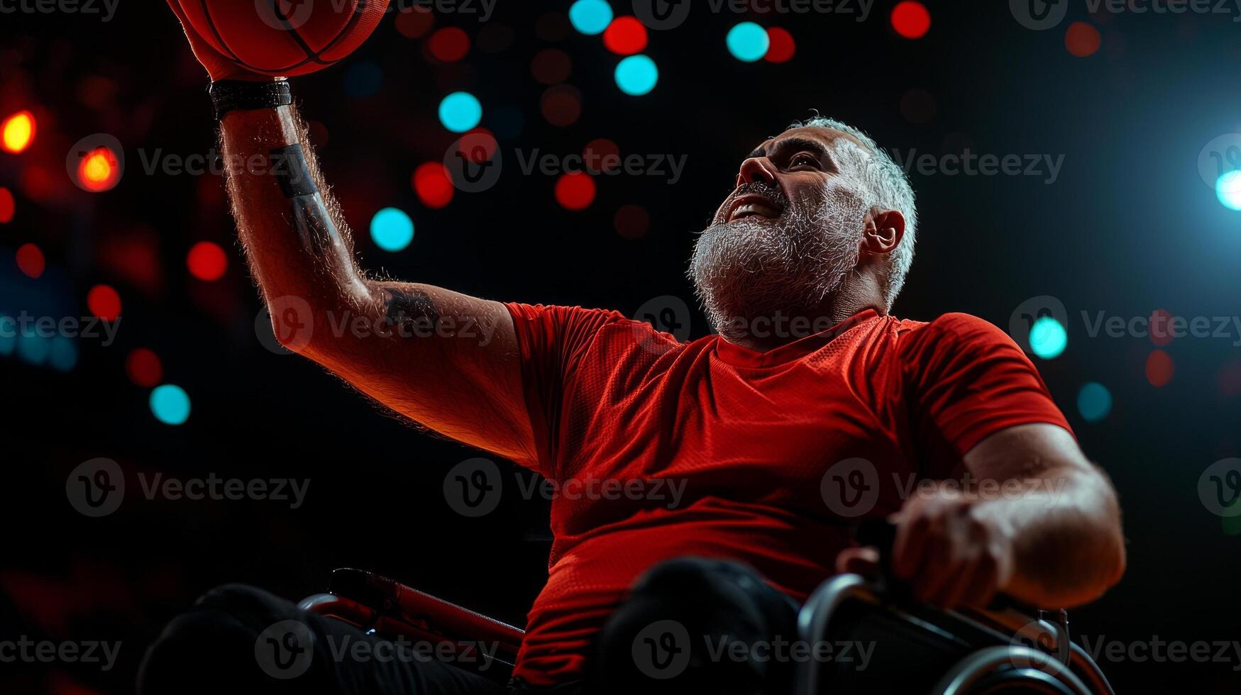 Hispanic amputee in dynamic pose plays wheelchair basketball while grasping chair and reaching for ball prosthetic arm amid colorful gymnasium lighting photo