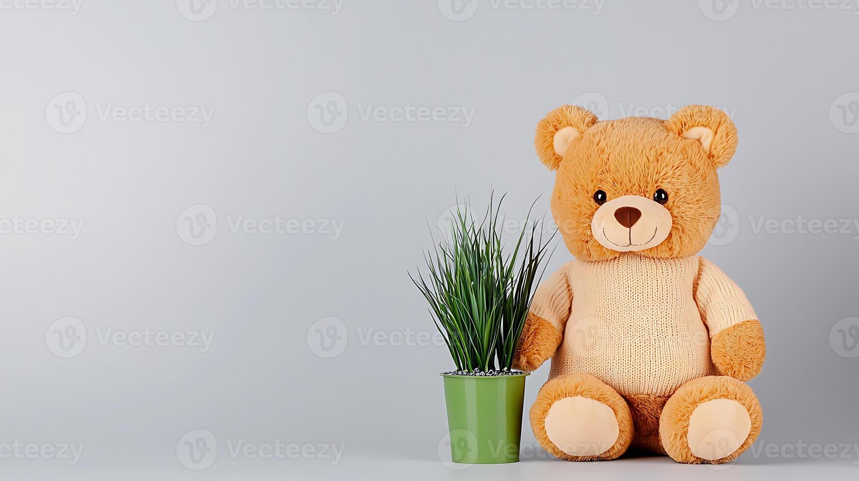 A teddy bear is sitting next to a plant photo