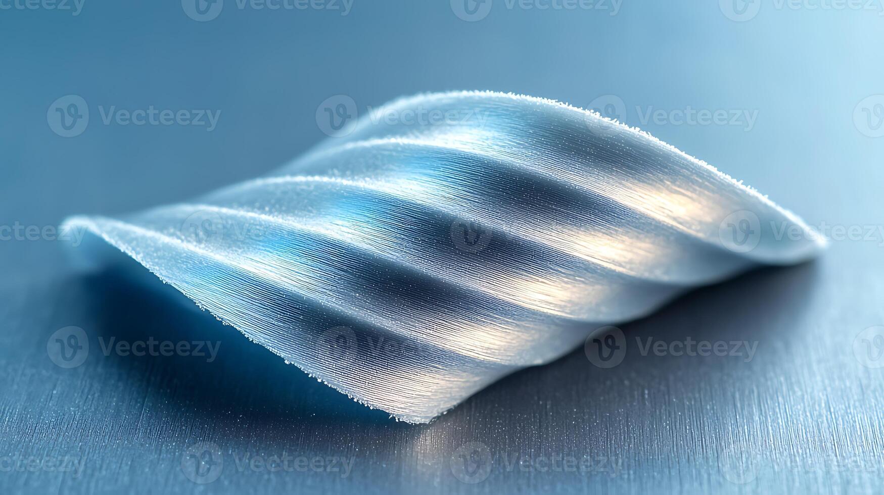 Close-up of a textured, wave-shaped metallic object reflecting light on a smooth surface photo