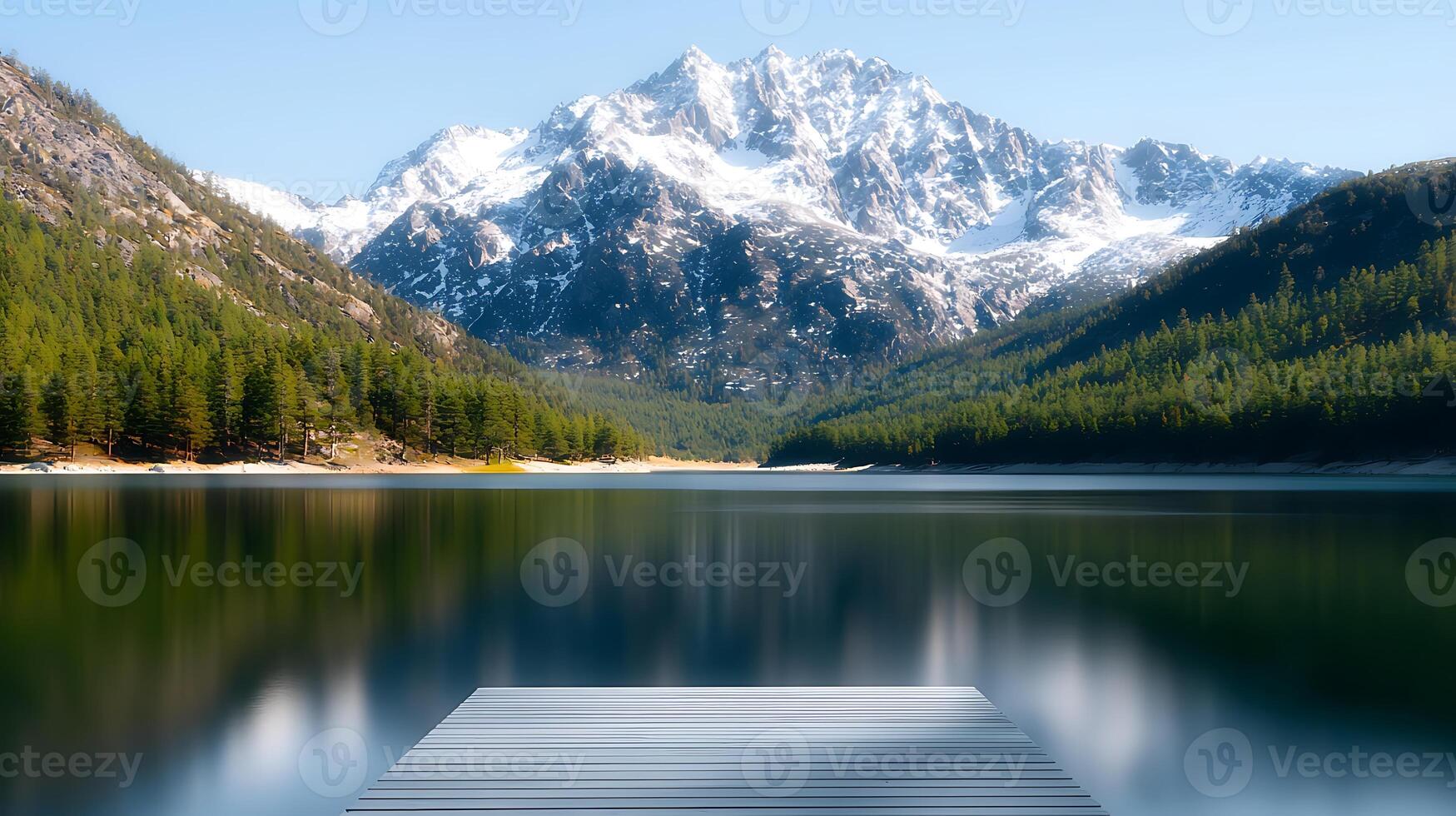 A dock in front of a mountain lake with snow capped mountains in the background photo