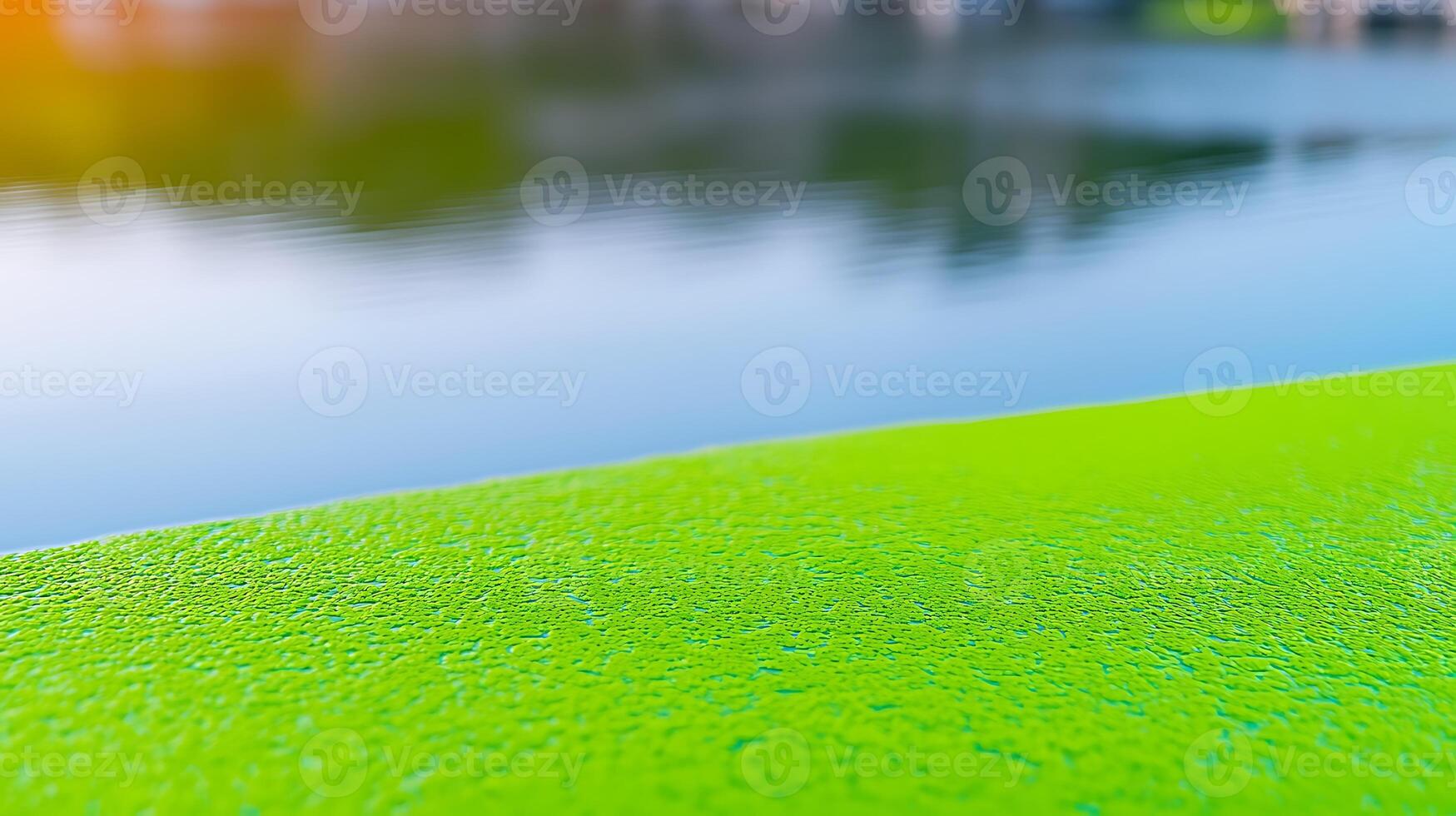 A green surface next to a body of water photo