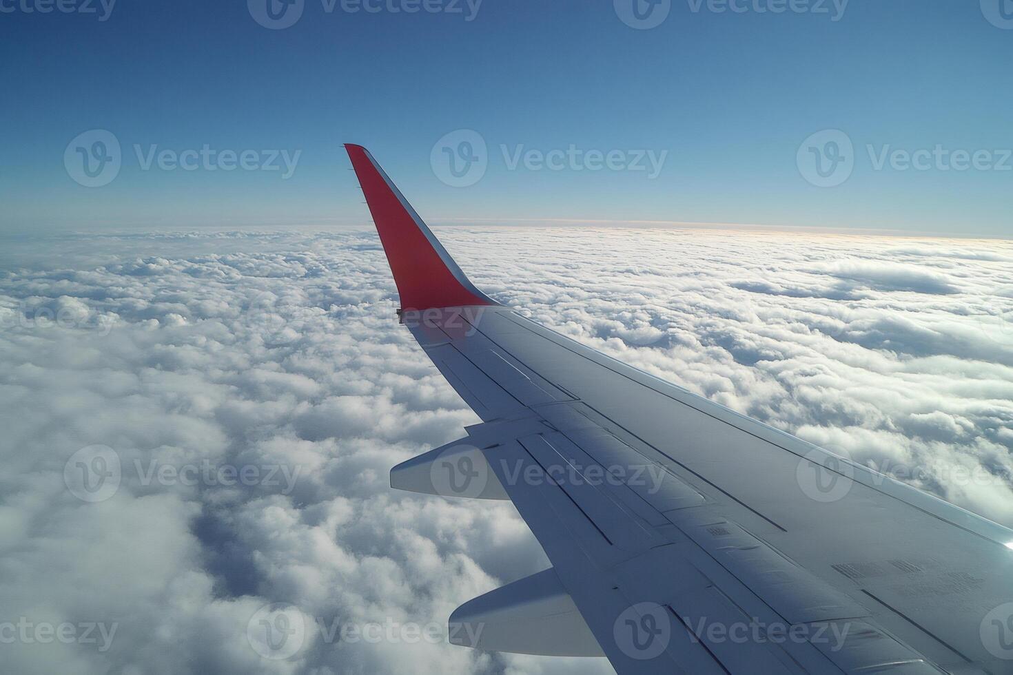 Airplane wing flying above the clouds in a beautiful sunny day photo