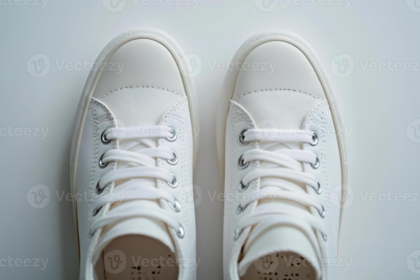 Pair of new white sneakers on white background with tied laces seen from above photo