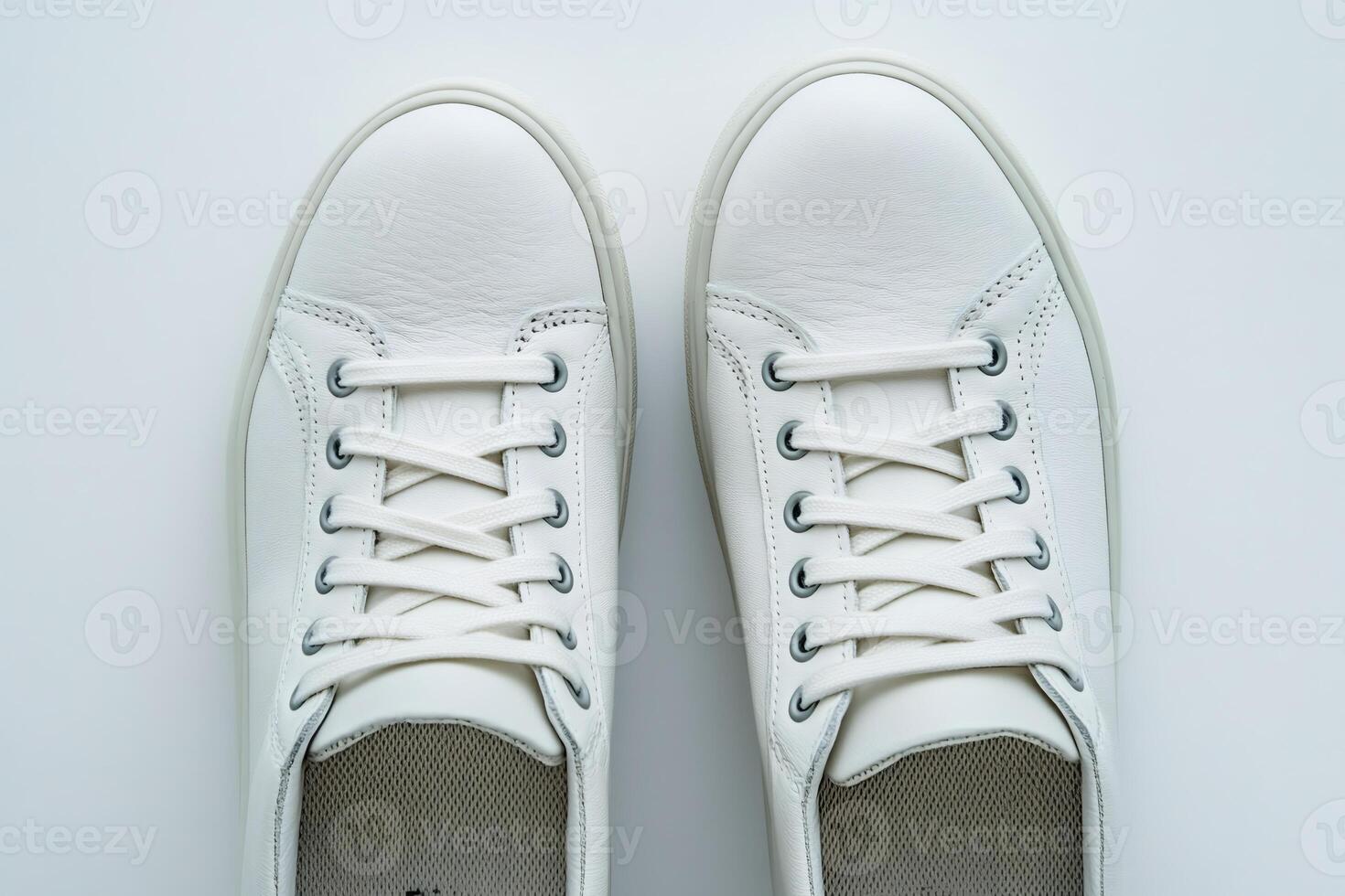 Pair of white leather sneakers with tied laces on white background photo