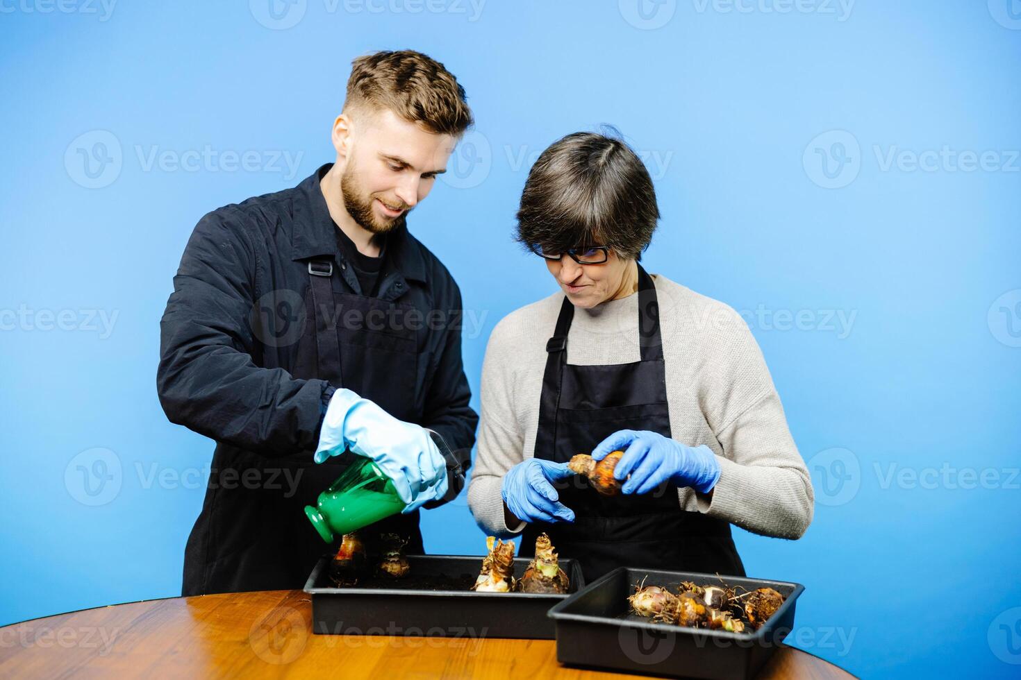 Working couple in a family business of florist store, they plants the flowers on the pot together and enjoy photo