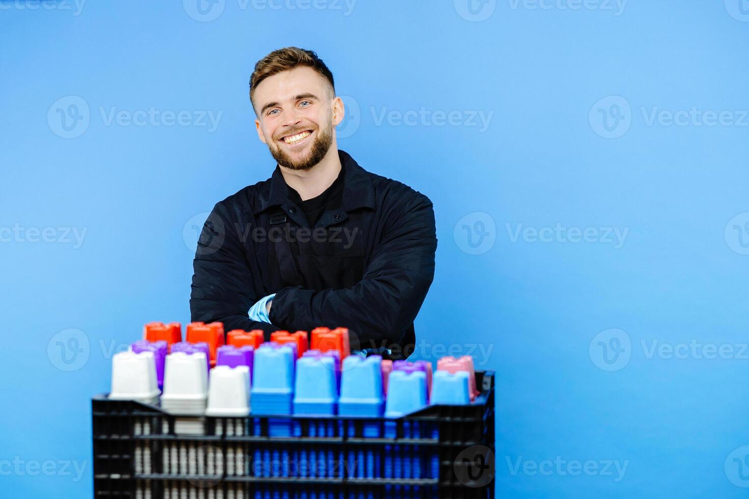 Man holding basket full of small pots for plants on blue background. photo