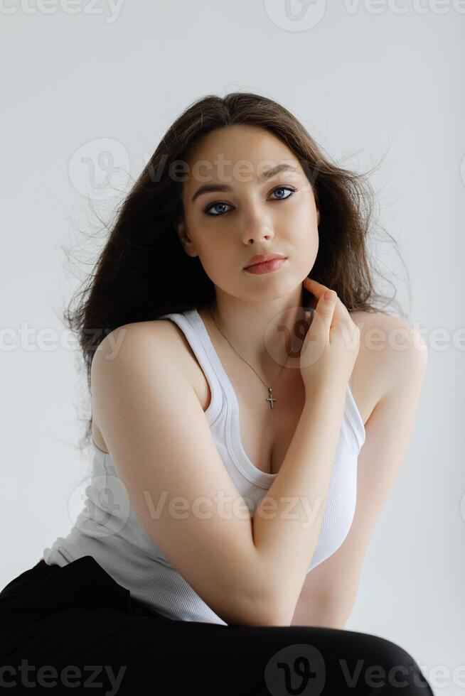 Young woman sitting on stool posing in studio with white background. photo