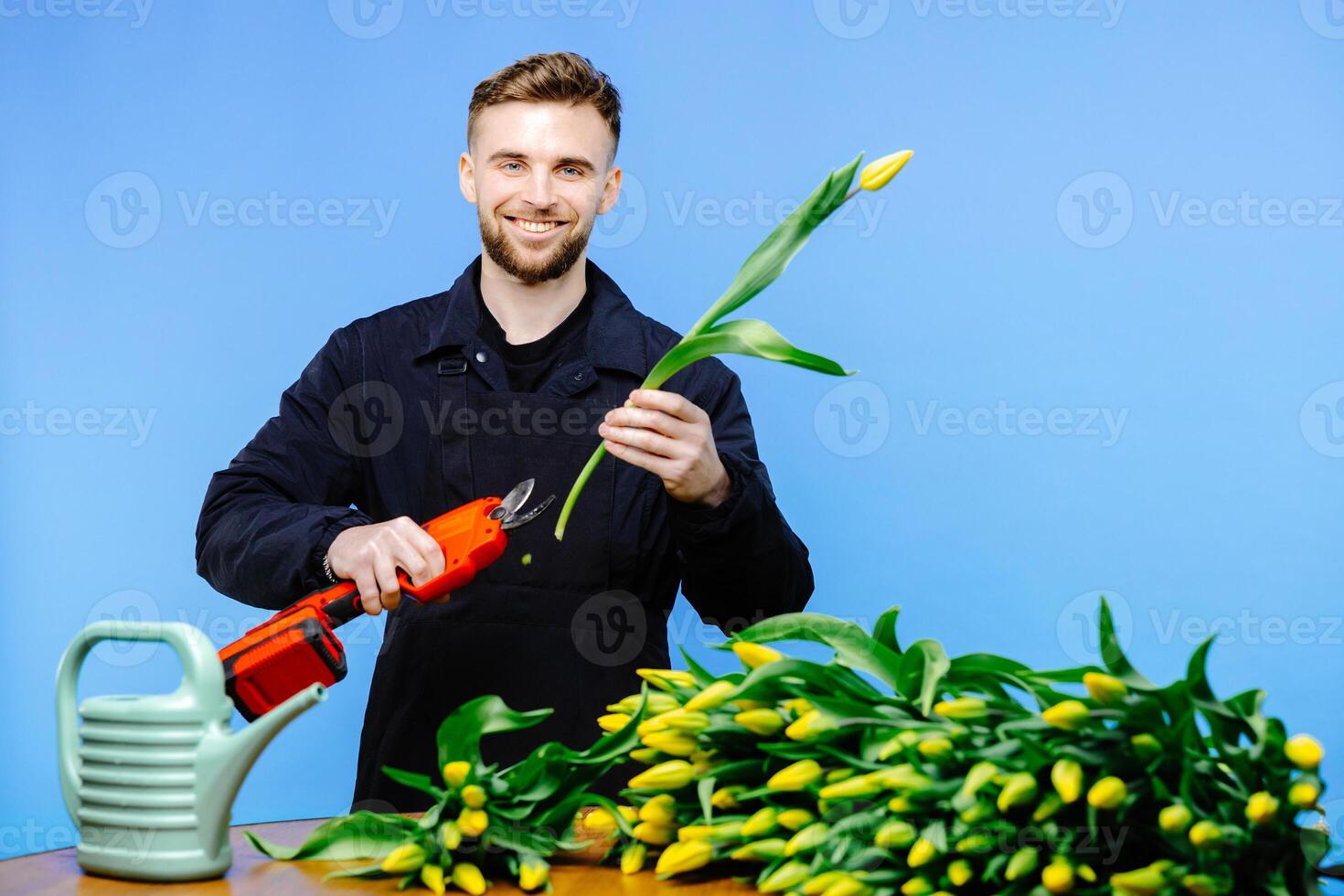 Man flower shop manager standing in apron in small floral shop. Man working a with tulips in flower shop photo