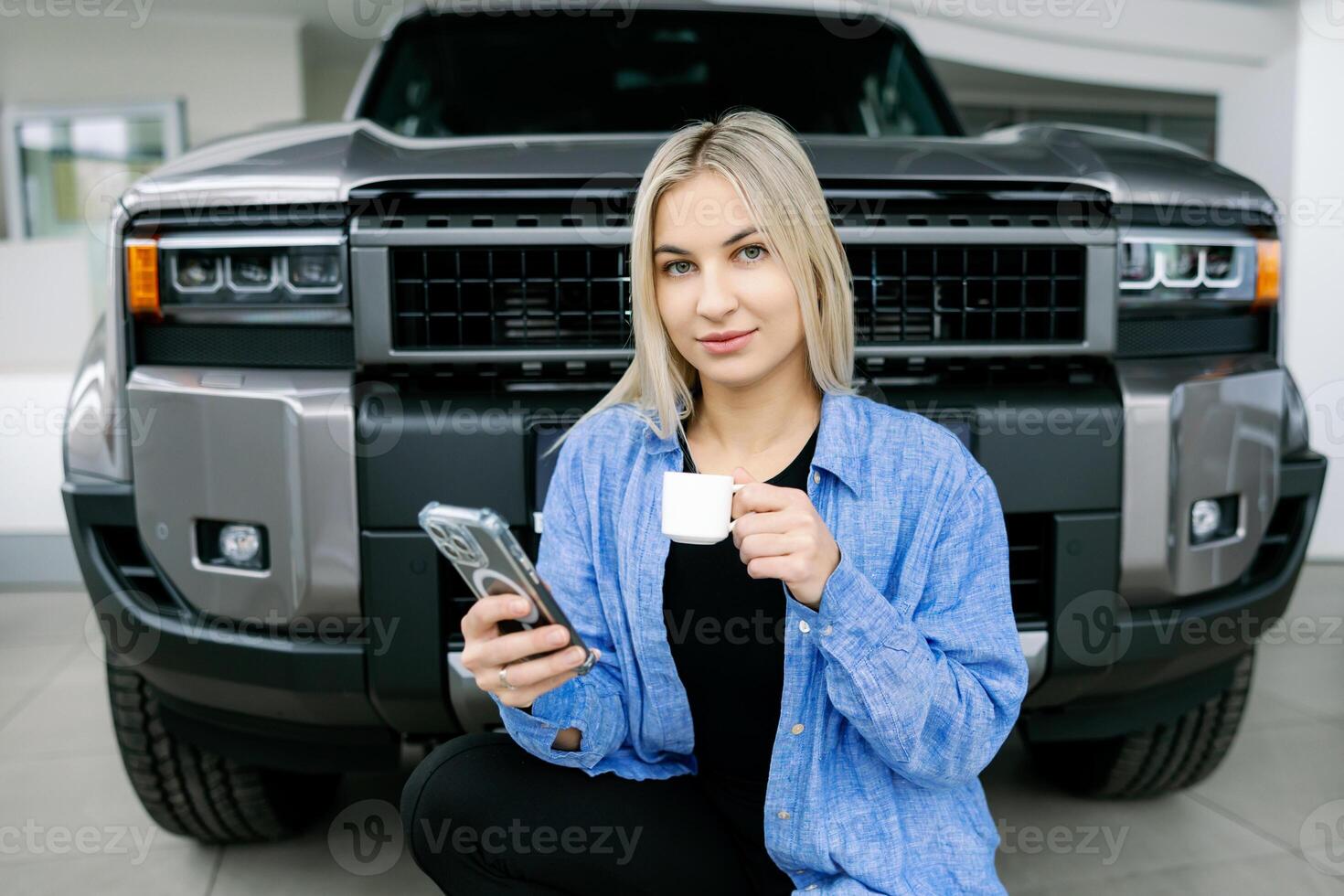 Saleswoman drinking coffee and using smartphone in front of pickup truck photo