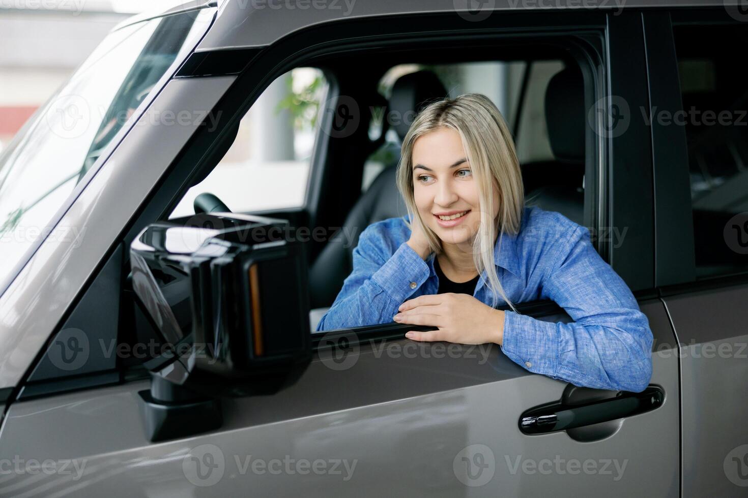 Happy customer smiling while sitting in her new car at the dealership. photo