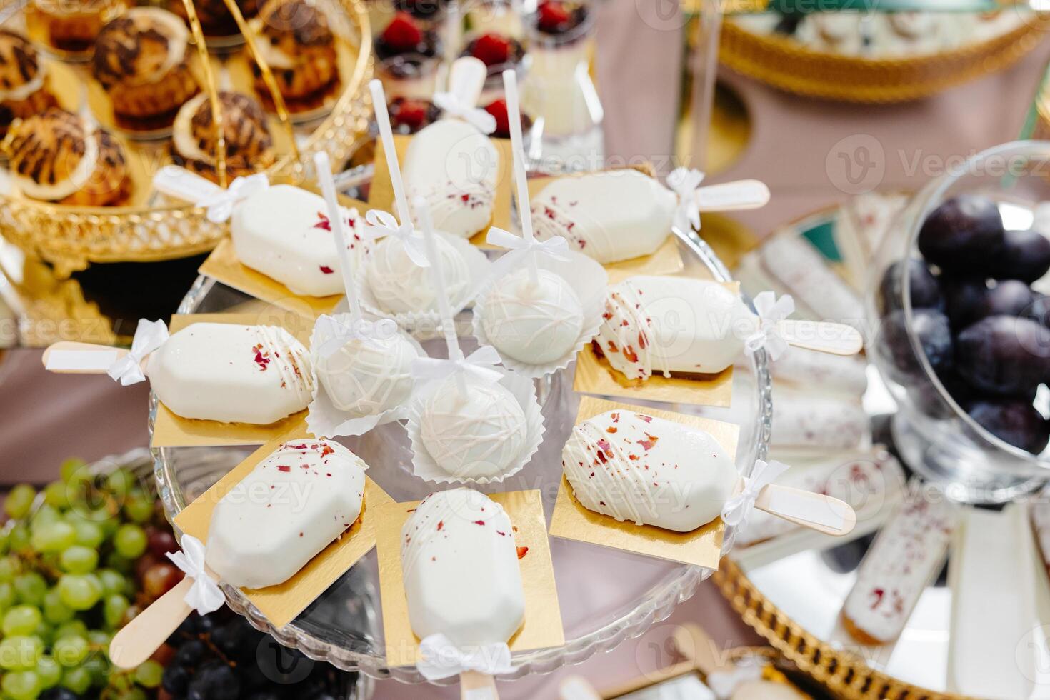 Delicious white chocolate cake pops and ice cream bars decorating a luxurious candy bar buffet. photo