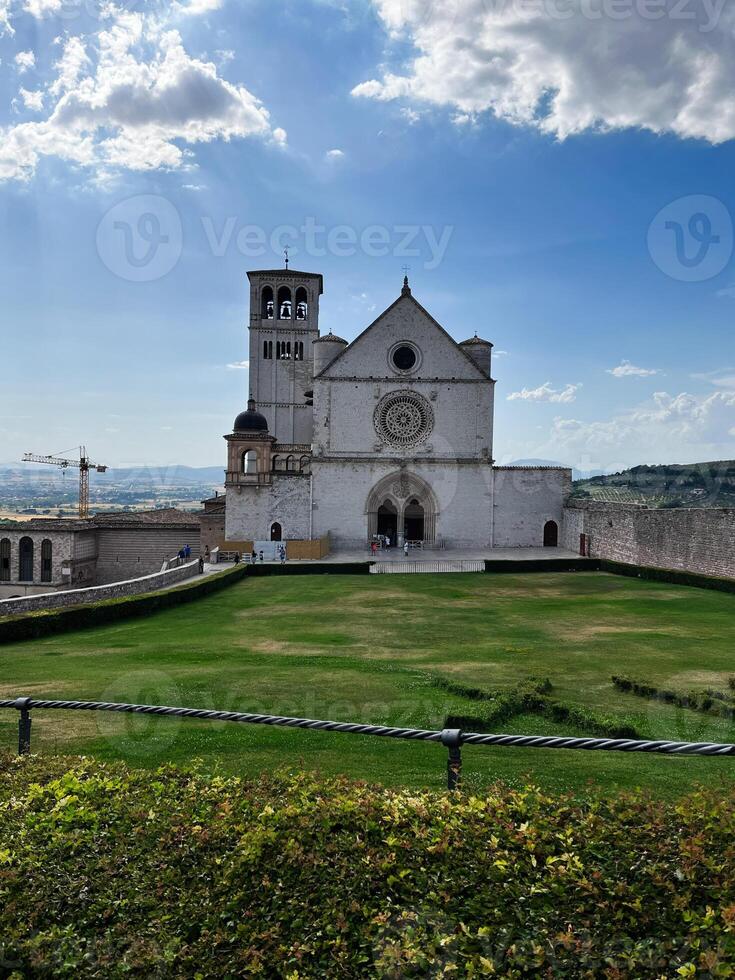 Scenic Basilica Against a Serene Landscape Under a Partly Cloudy Sky, Assisi, Italy. photo