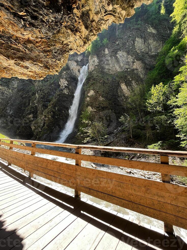 Wooden bridge overlooking a scenic waterfall in a lush forested canyon. Liechtensteinklamm, Austria. photo