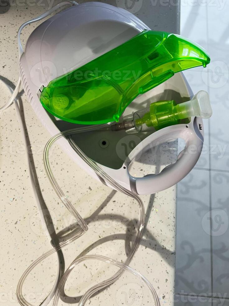 Compact nebulizer machine with green chamber on a light surface photo