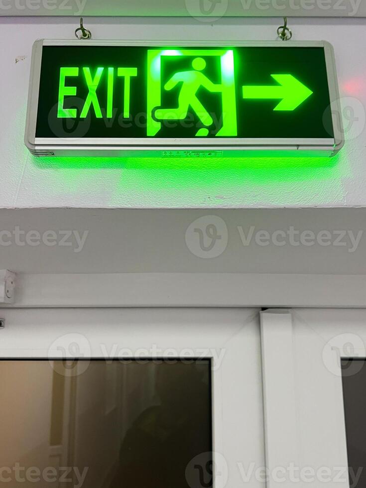 Illuminated green exit sign above a door indicating a safe evacuation route photo