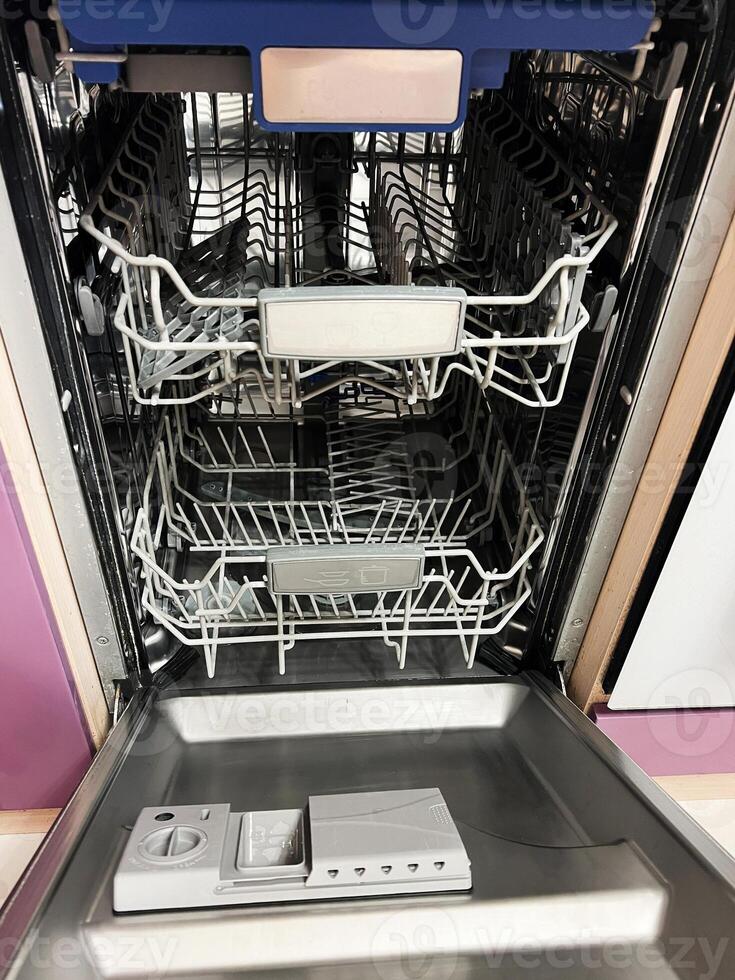 Modern stainless steel dishwasher with empty racks and detergent dispenser photo