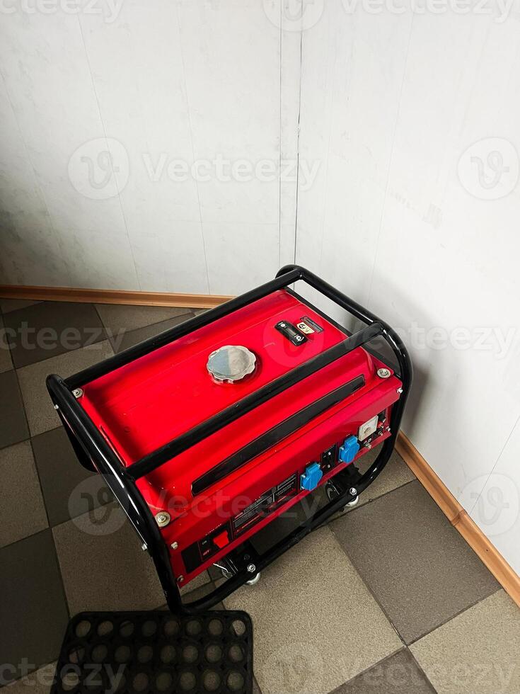 Portable red generator placed indoors on tiled flooring photo