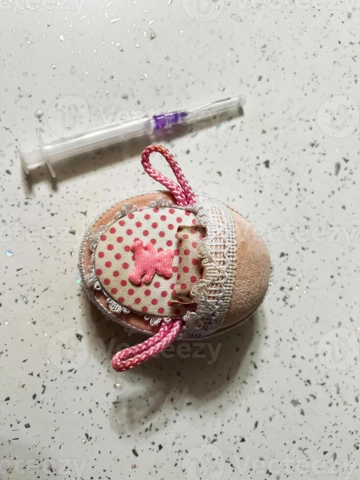 Decorative Fabric Pouch Accompanied by a Small Syringe on a Light Surface photo