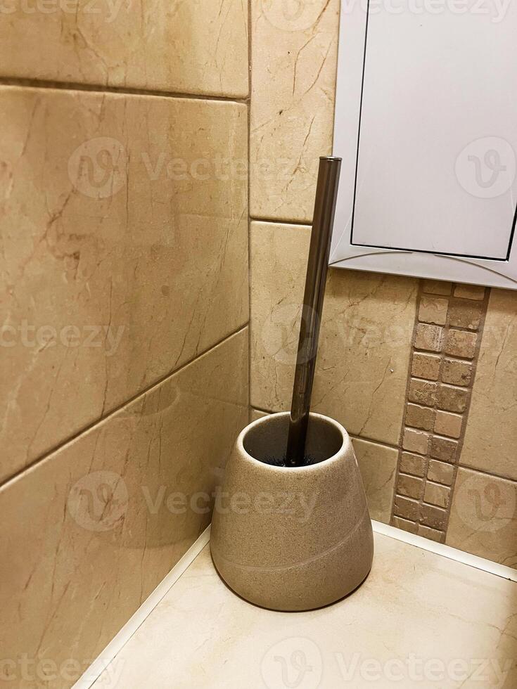 Bathroom cleaning brush with holder on a tiled wall background photo