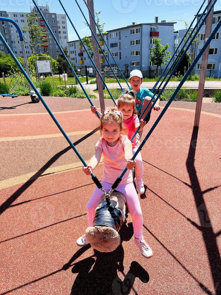 Children playing together on a swing in an outdoor playground photo