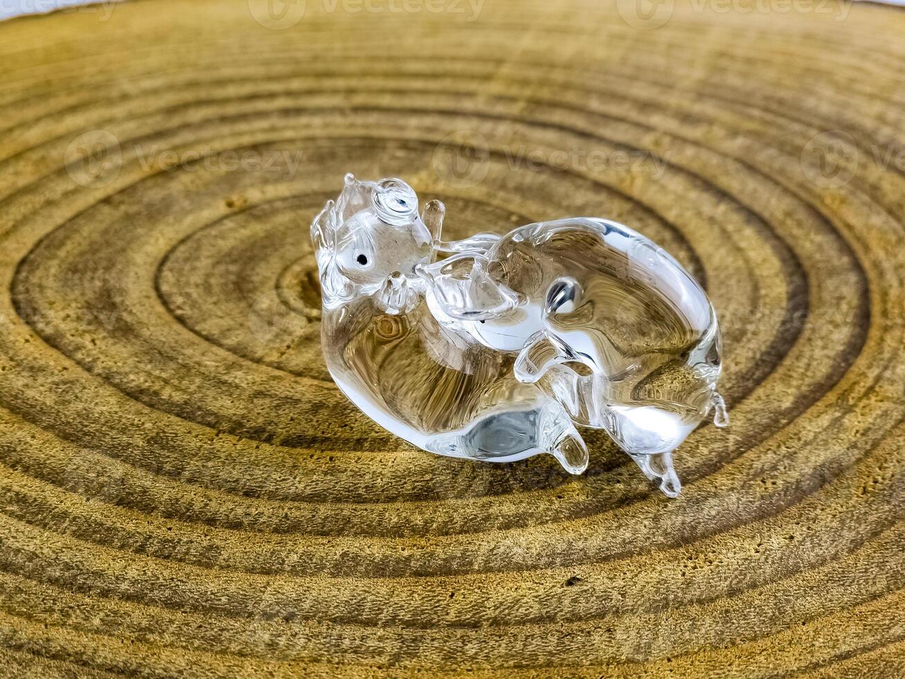 Glass figurine in the form of kissing piglets on a wooden background. Transparent glass photo
