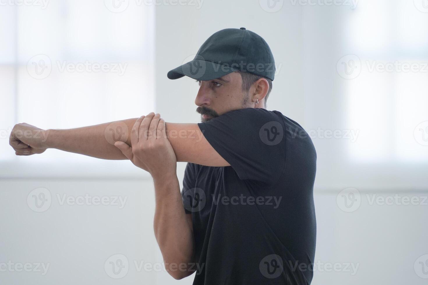 Warm Up. Muscular man stretching his arms and shoulders before gym workout. photo