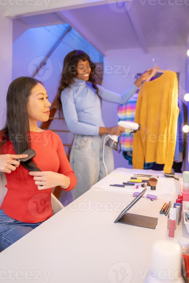 Multiethnic friends putting on some makeup before going out at night. Black and Chinese women. photo