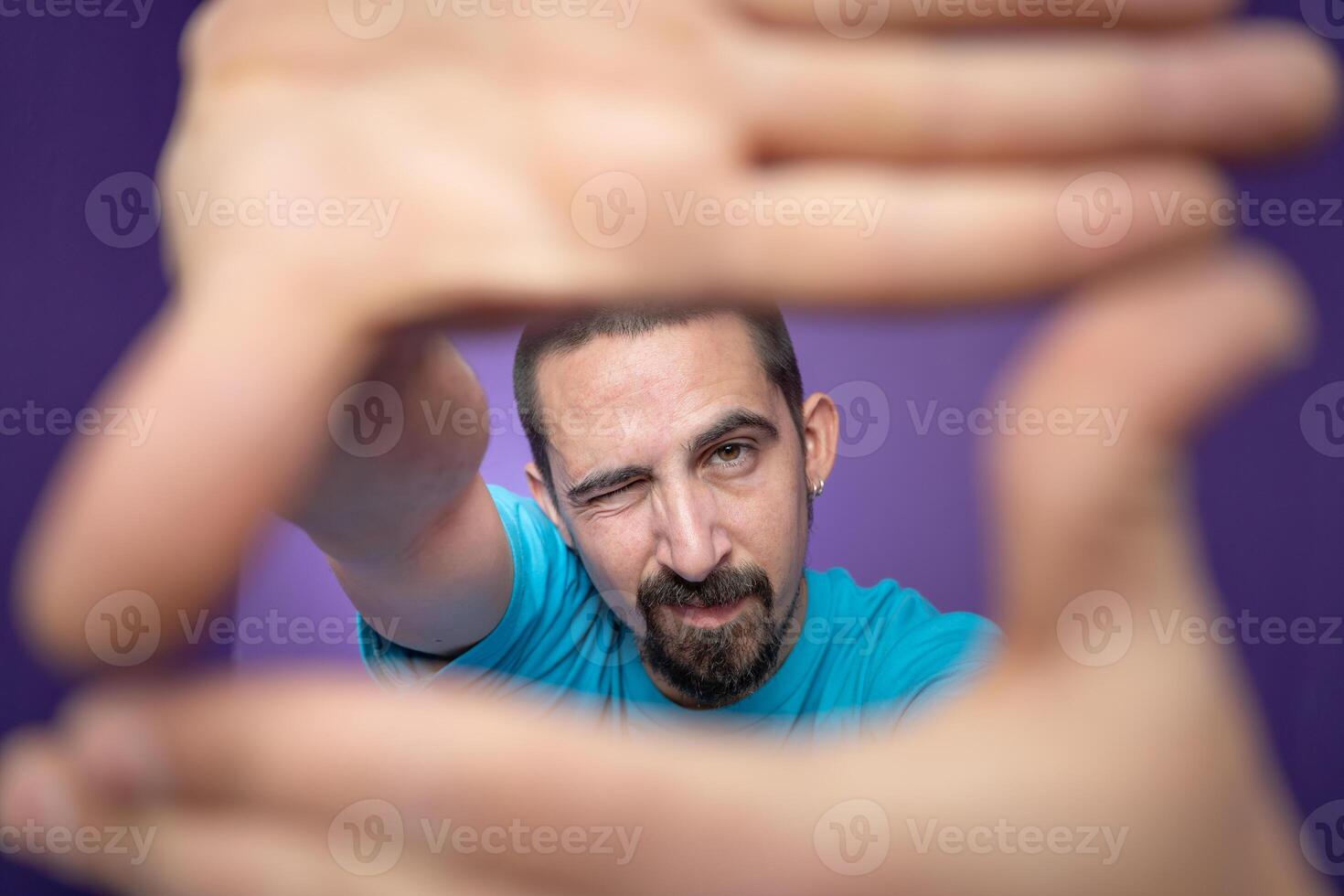 Young handsome man doing frame using hands palms and fingers, over purple background photo
