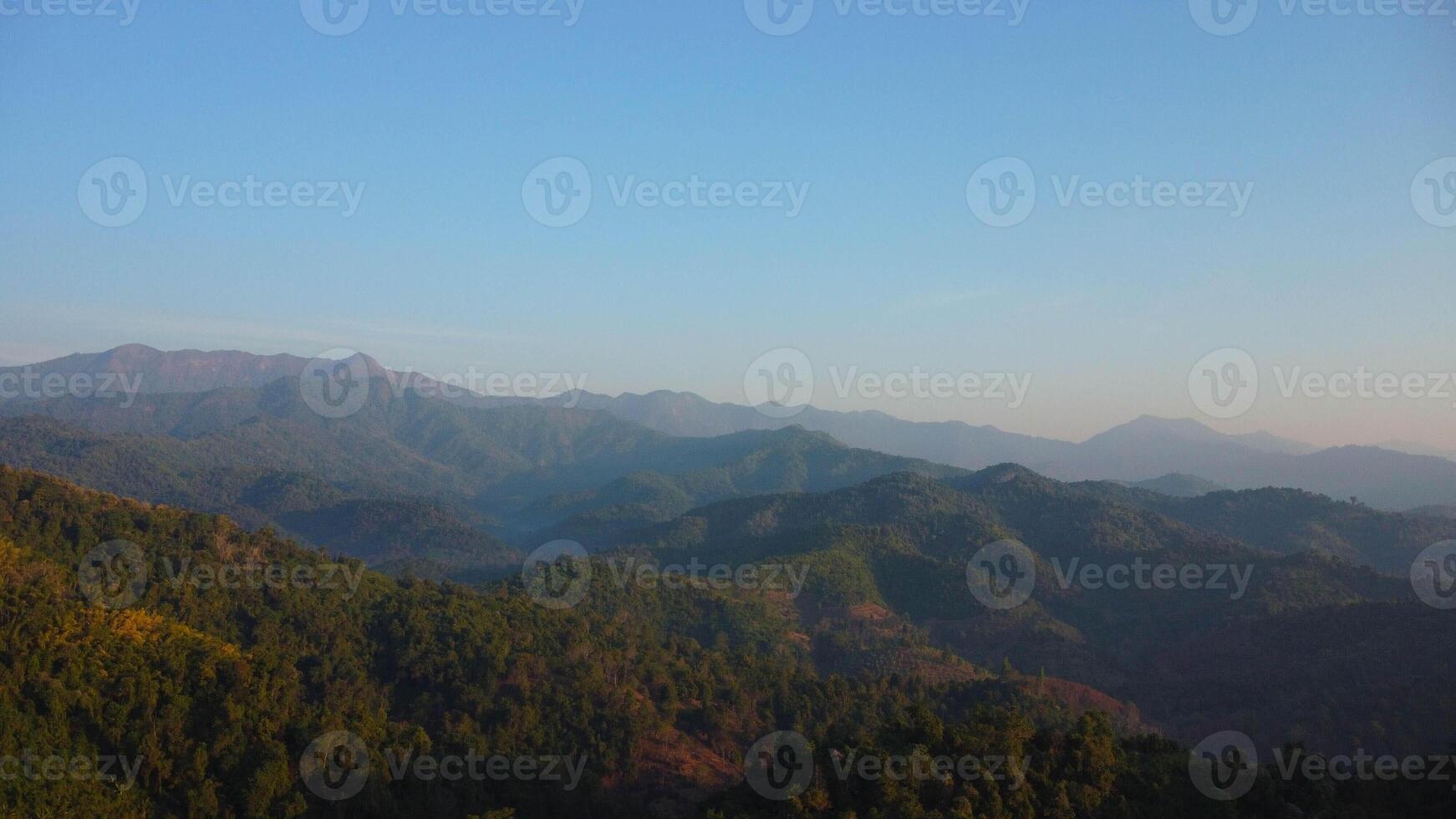Beautiful sunrise on the mountain with fog in winter. The sun shines down on a serene mountain landscape covered with tropical. photo