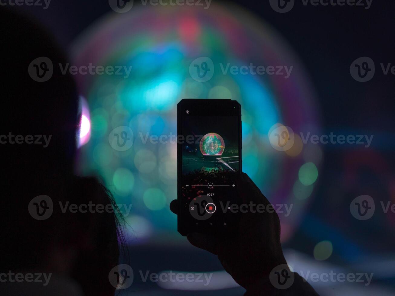 Tourists are filming a light and sound show using their smartphones photo