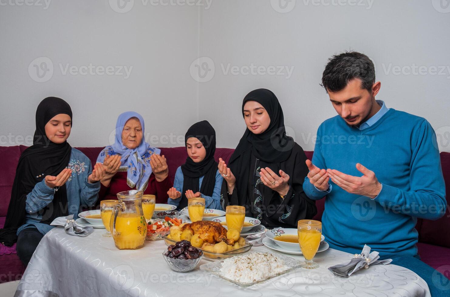 Muslim family making iftar dua to break fasting during Ramadan happy parents having dinner with their children and grandmother at dining table at home. photo